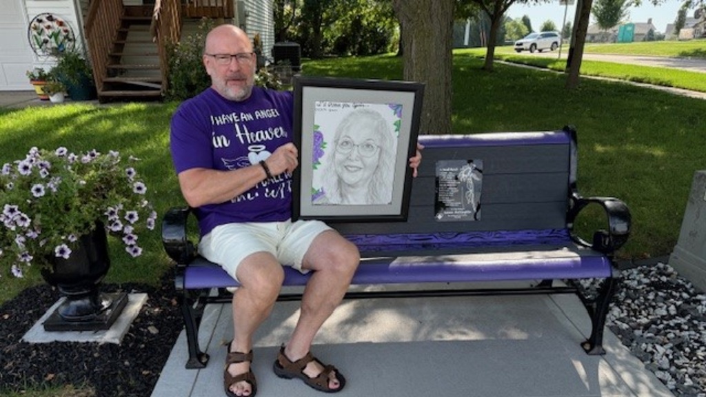 Dave McGlaughlin sitting on a bench with a photo of his wife Jenna